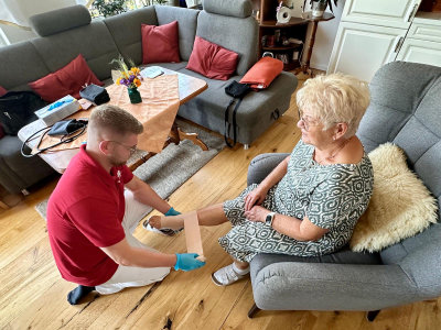 Ein Pfleger legt einer Patientin zuhause einen Fußverband
